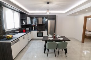 Eine moderne Küche mit Essbereich, ausgestattet mit Geschirrspüler, Backofen und einem für zwei Personen gedecktem Esstisch.