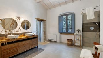 Un bagno moderno con un mobile bagno in legno, due specchi rotondi, una grande finestra e una zona doccia.