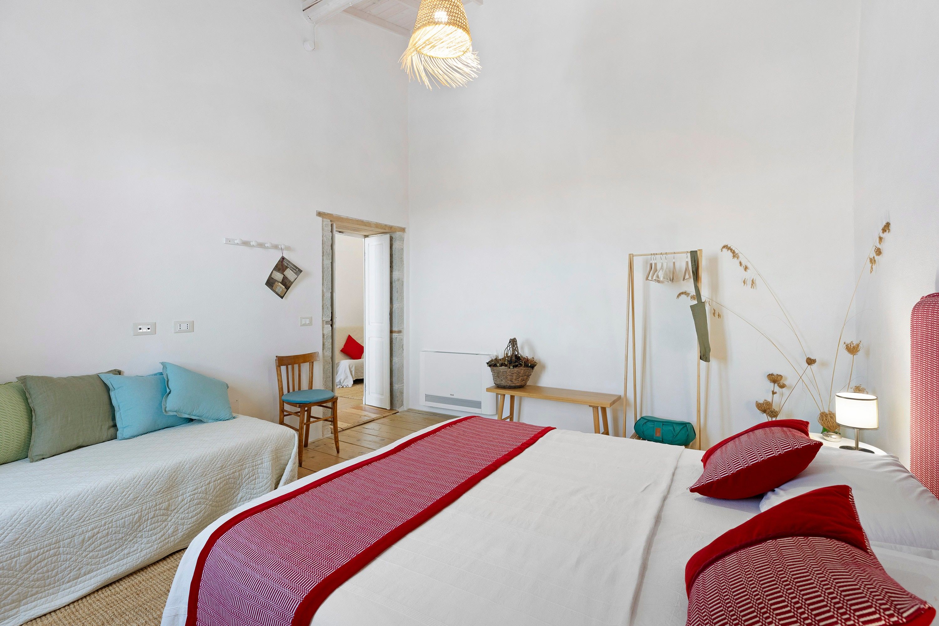 A hotel room with a bed, a chair, a table, and a mirror.