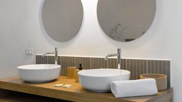 A bathroom with two large oval mirrors, a wooden vanity, and a white towel.