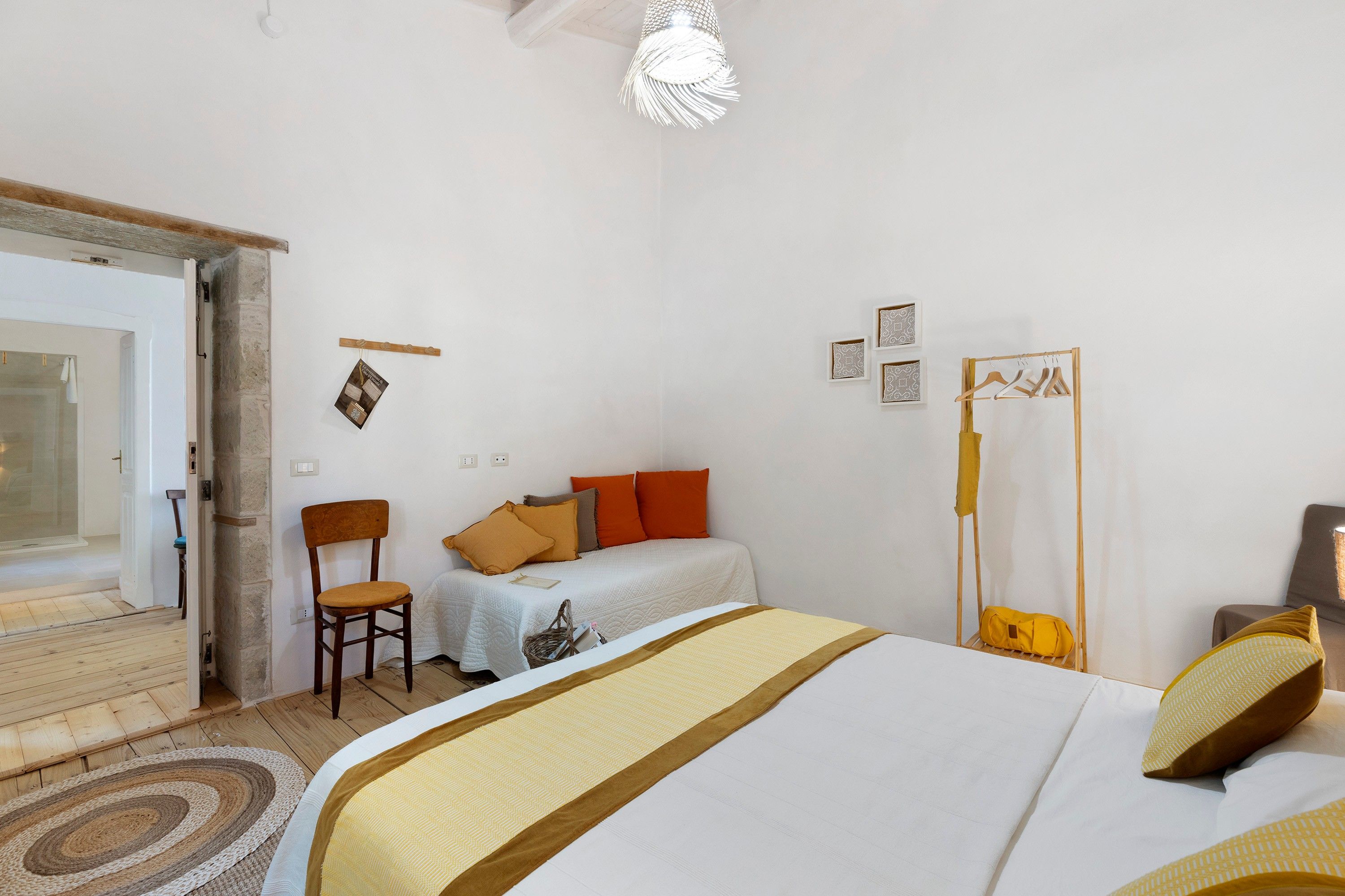 Ein Schlafzimmer mit Bett, Sessel, Nachttisch, Pendelleuchte und Kleiderschrank.