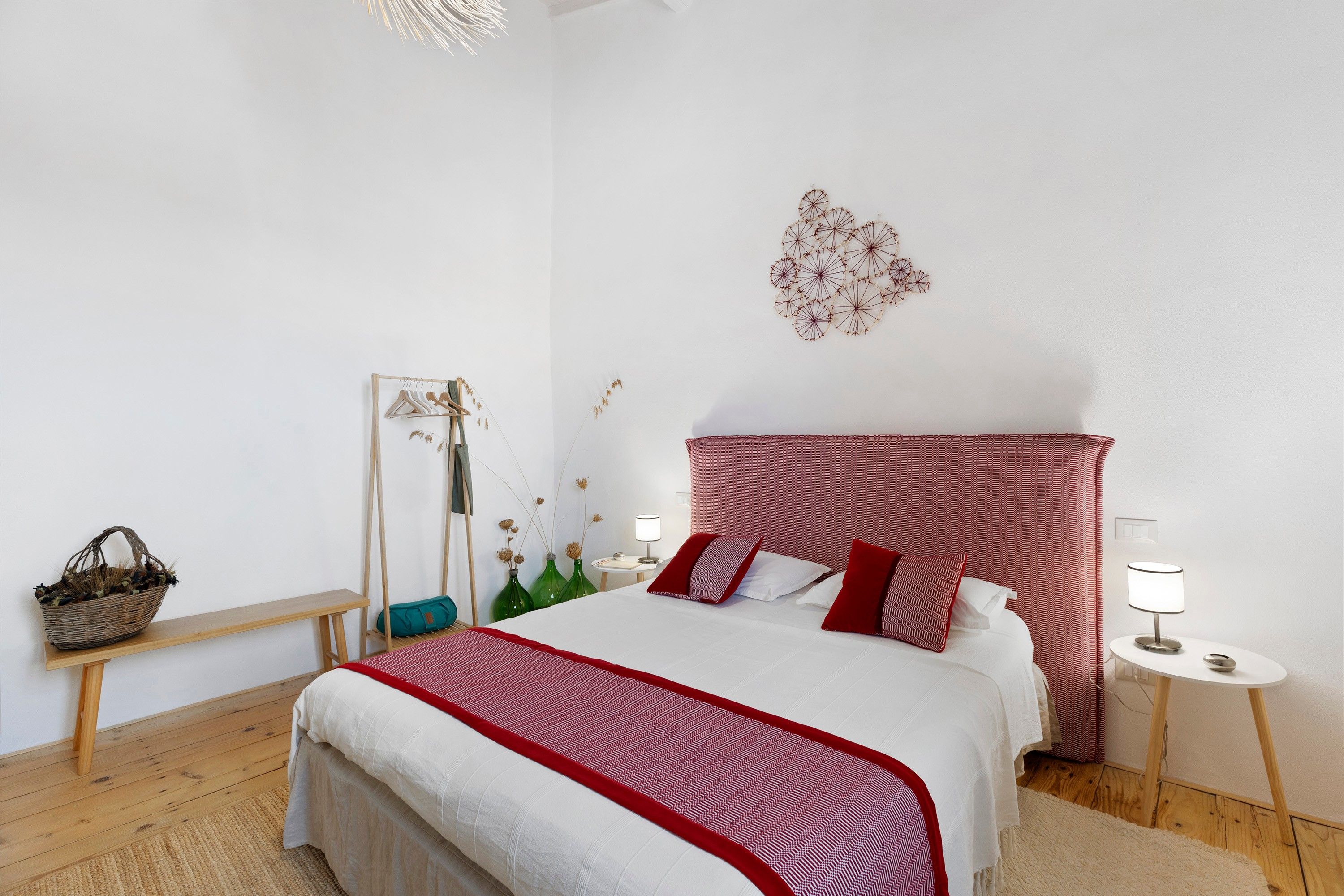 Ein Schlafzimmer mit einem Bett, Nachttischen, einem Hängesessel und einer Wanddekoration.