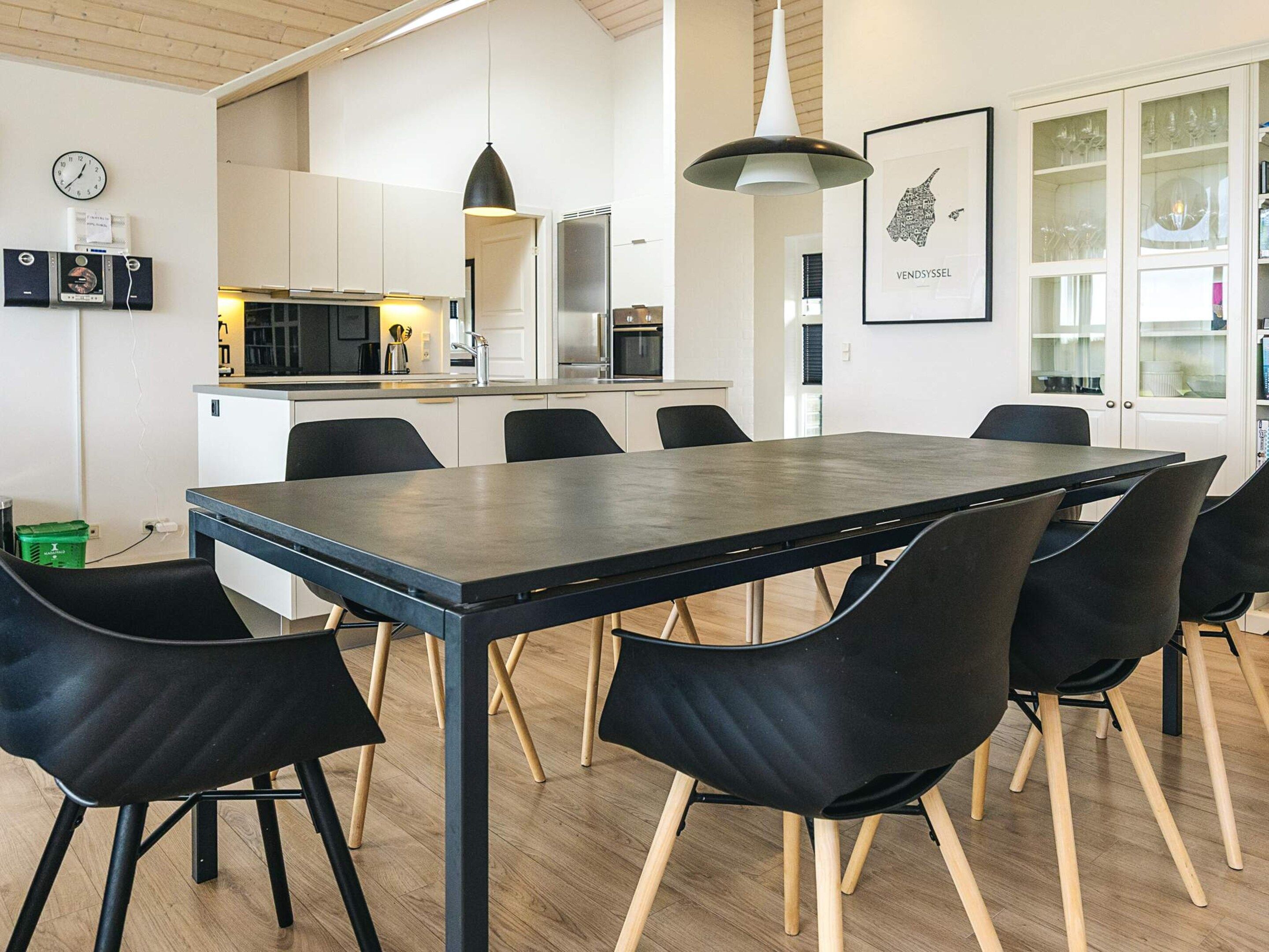 Een moderne keuken met witte kasten, een zwart aanrecht en een roestvrijstalen koelkast.