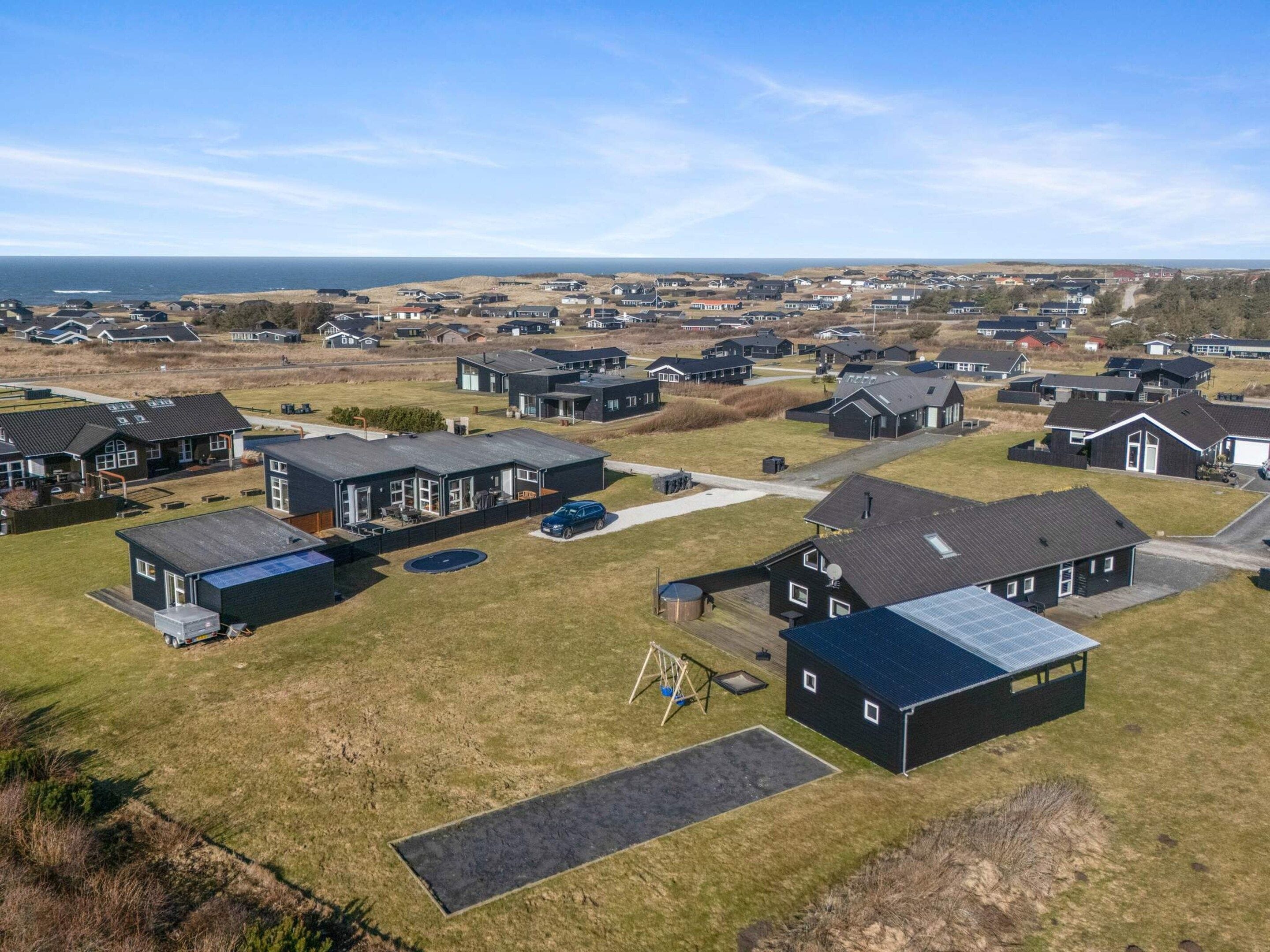 Ett bostadsområde med hus, en lekplats och utsikt över havet.