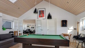 A modern living room with a pool table, wooden ceiling, and a dining area. - 5 Star Holiday Home in Lokken (Lokken)
