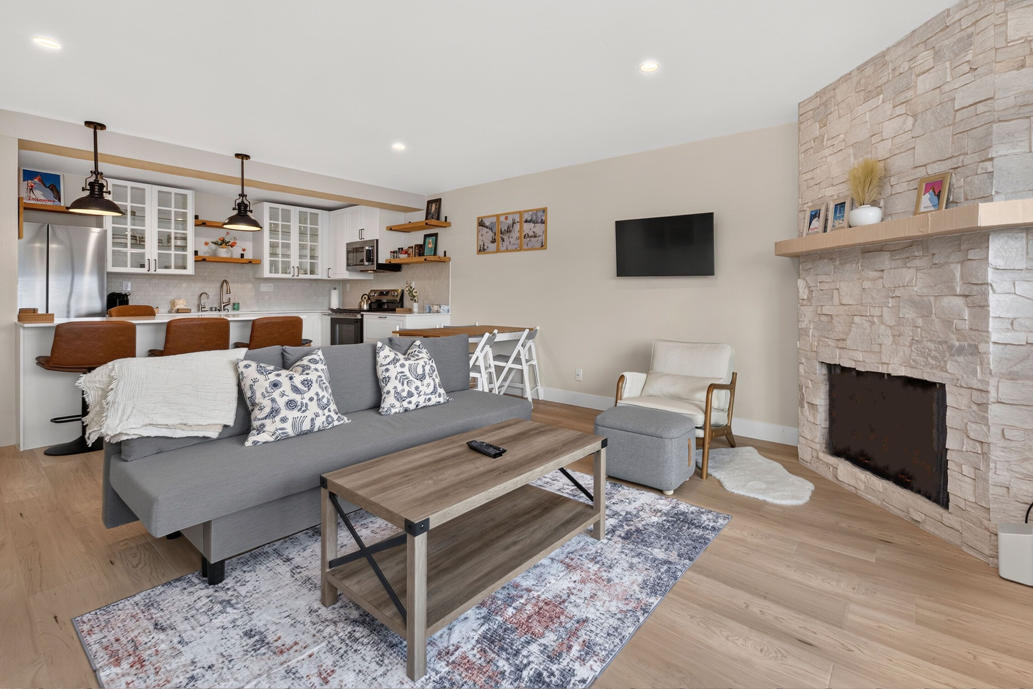 A modern living room with a grey sofa, wooden coffee table, and a fireplace.