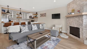 A modern living room with a grey sofa, wooden coffee table, and a fireplace.