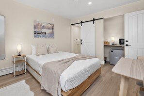 A bedroom with a bed, bedside tables, a painting, a wardrobe, a desk, and a refrigerator. - Winter Park Lodge II Unit E102 Renovated, mt views, 2 bedroom with amenities (Fraser)