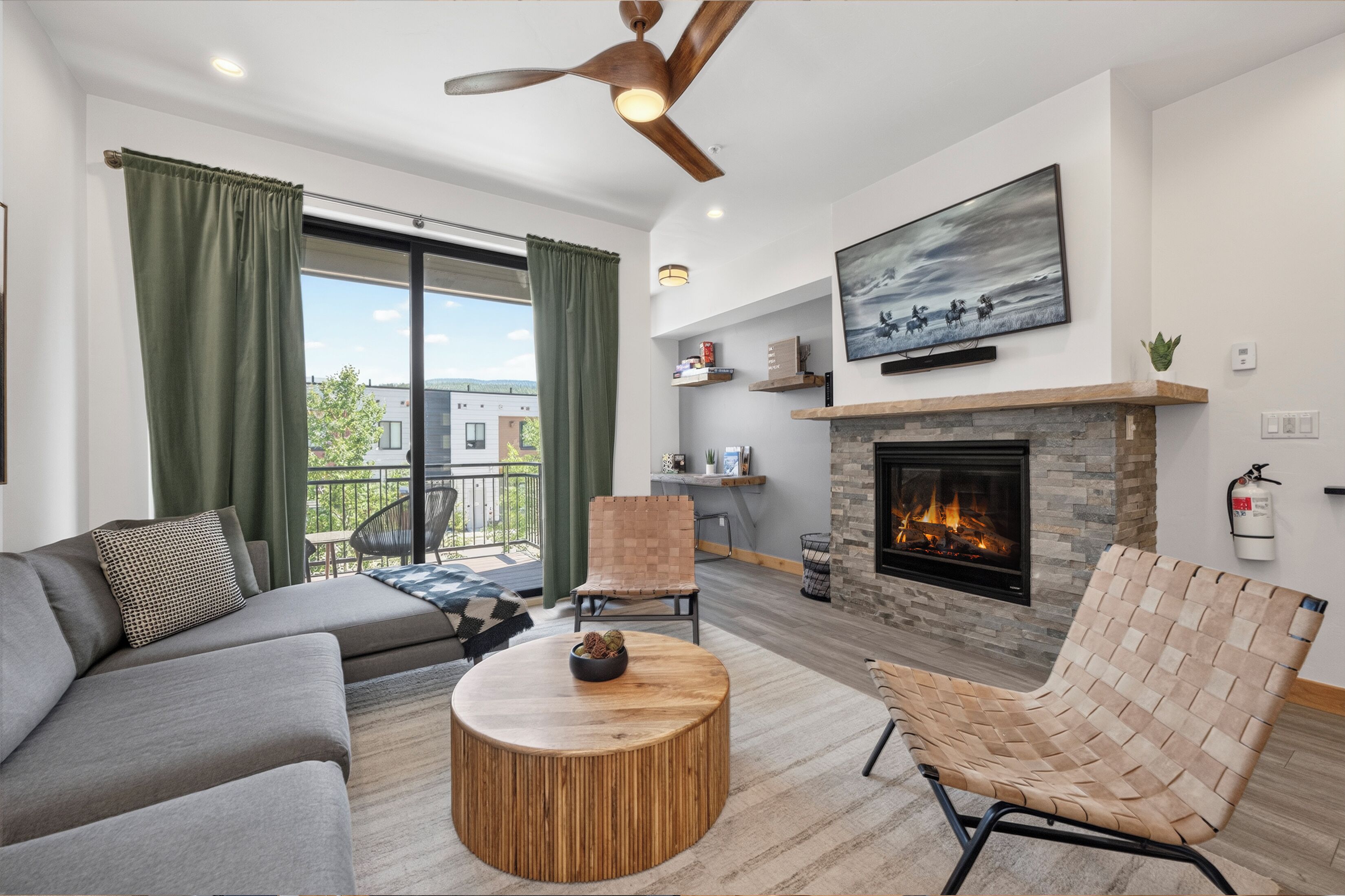 A modern living room with a fireplace, a sofa, a chair, and a television mounted above the fireplace.