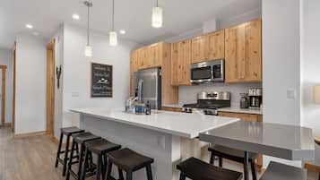 A modern kitchen with wooden cabinets, stainless steel appliances, and a central island with bar stools.