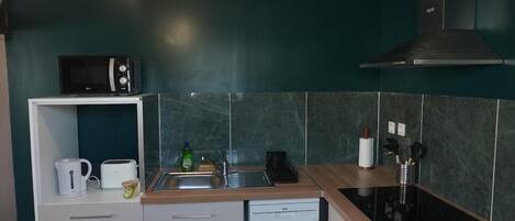 Cocina compacta con microondas, tostadora y pileta.