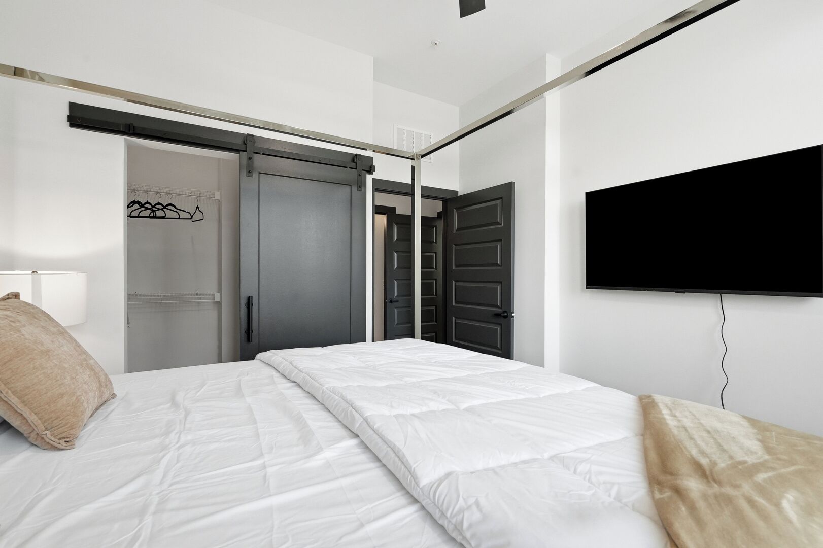 A hotel room with a bed, a television mounted on the wall, and a sliding door closet.