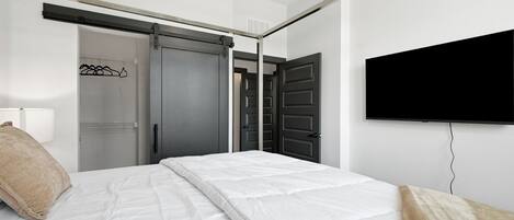 A hotel room with a bed, a television mounted on the wall, and a sliding door closet.