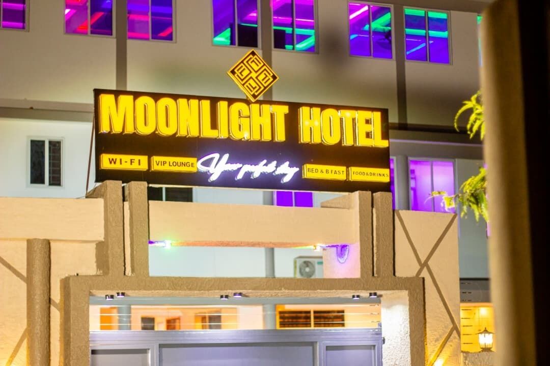 A sign for the Moonlight Hotel with amenities like Wi-Fi, VIP lounge, and food & drinks.