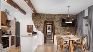 Una cocina moderna con pared de piedra, vigas de madera y un comedor con una mesa redonda y sillas de mimbre.