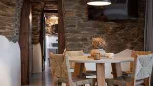 Comedor con pared de piedra, una mesa redonda y sillas tejidas.