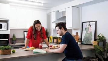 Una cocina moderna con armarios blancos, un microondas y una persona preparando comida.