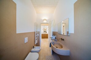 Une salle de bain moderne équipée d’un bidet, de toilettes et d’un lavabo.