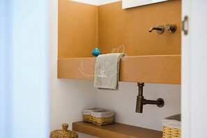 Een badkamer met een handdoek aan een handdoekhouder, een klein blauw decoratief object op de plank, en een mandje op het onderste plankje.