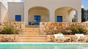 A modern building with a pool, stone steps, and two arched doorways. - TD Villa Antonia - Hidden Citrus Retreat (Ostuni)