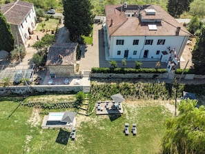 Un grand bâtiment doté d’un toit en tuiles, d’un mur en pierre et d’un espace verdoyant aménagé avec du mobilier d’extérieur.