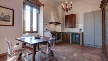 A kitchen with a dining table, chairs, a chandelier, and a large window.