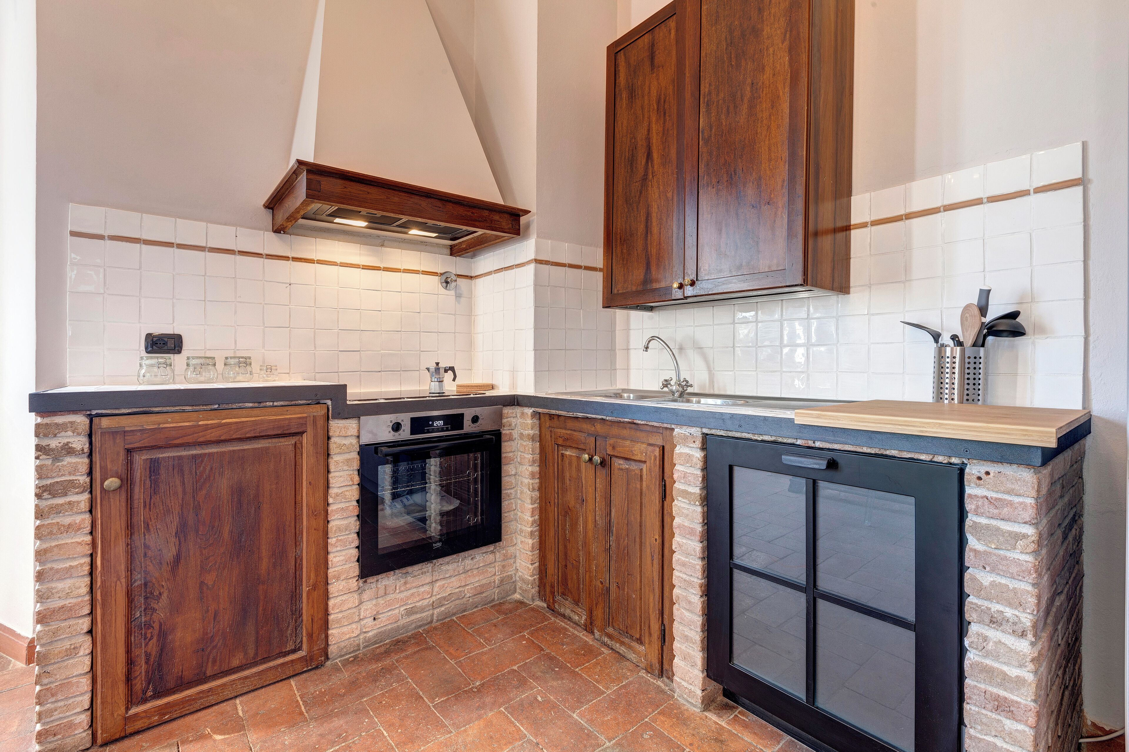 A compact kitchen with a built-in oven, a dishwasher, and wooden cabinets.
