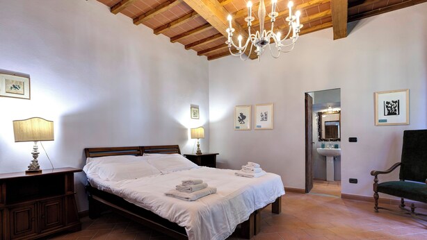 Un dormitorio con cama de madera, lámparas de noche, una araña y obras de arte en las paredes.