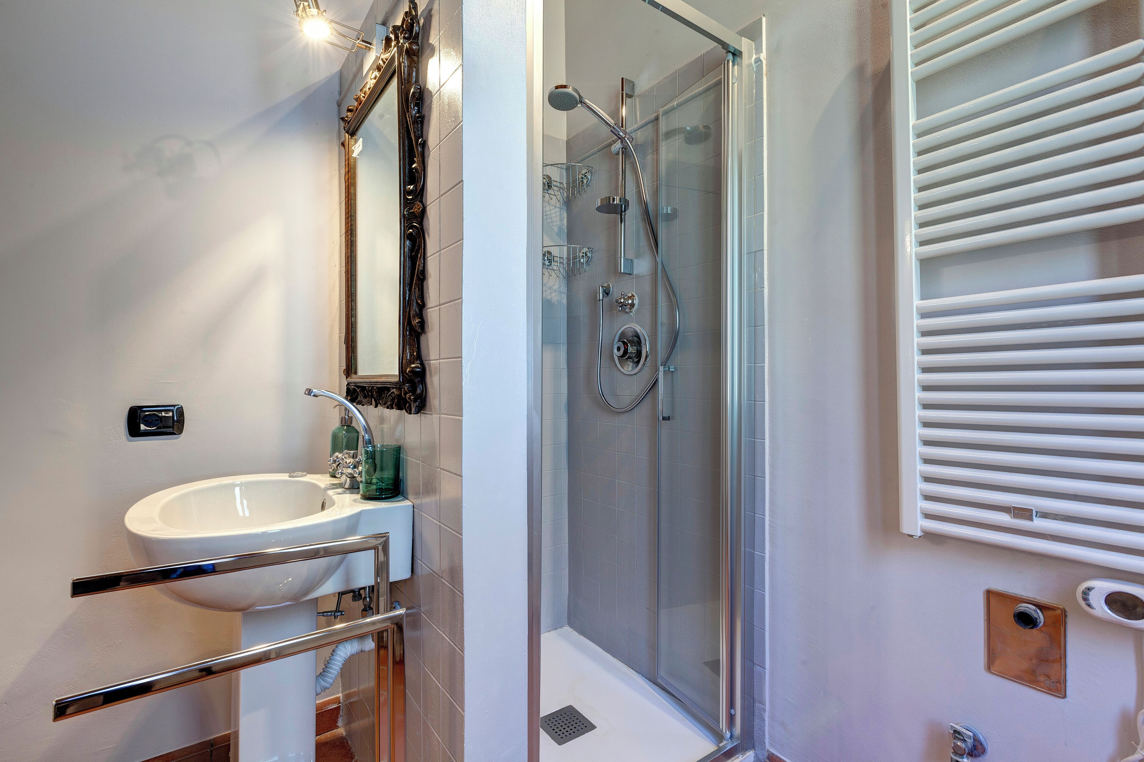 Un bagno con doccia vetro, lavabo con specchio e porta asciugamani.