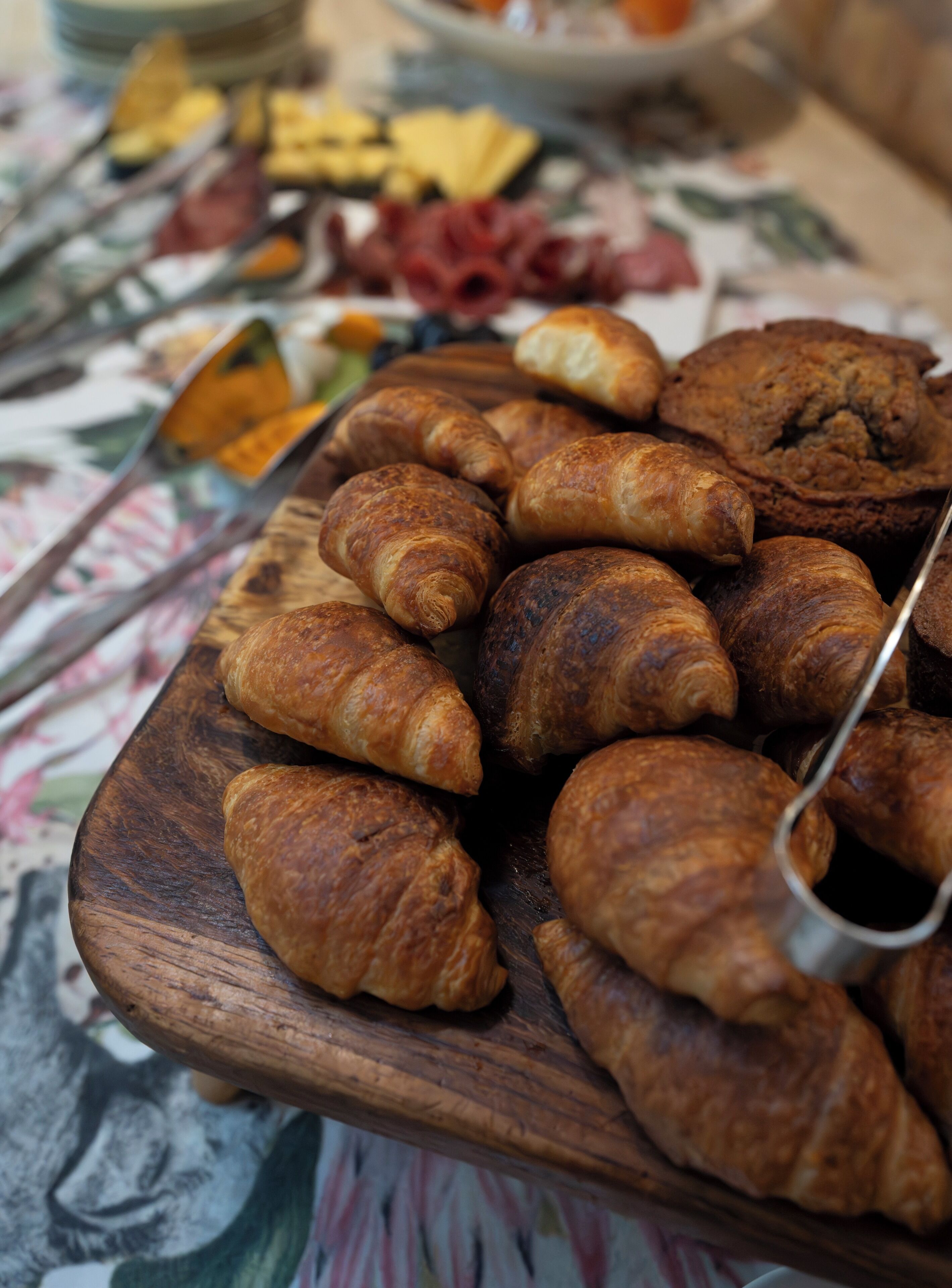 Una tabla de madera con varios croissants y un expositor para pastelería.