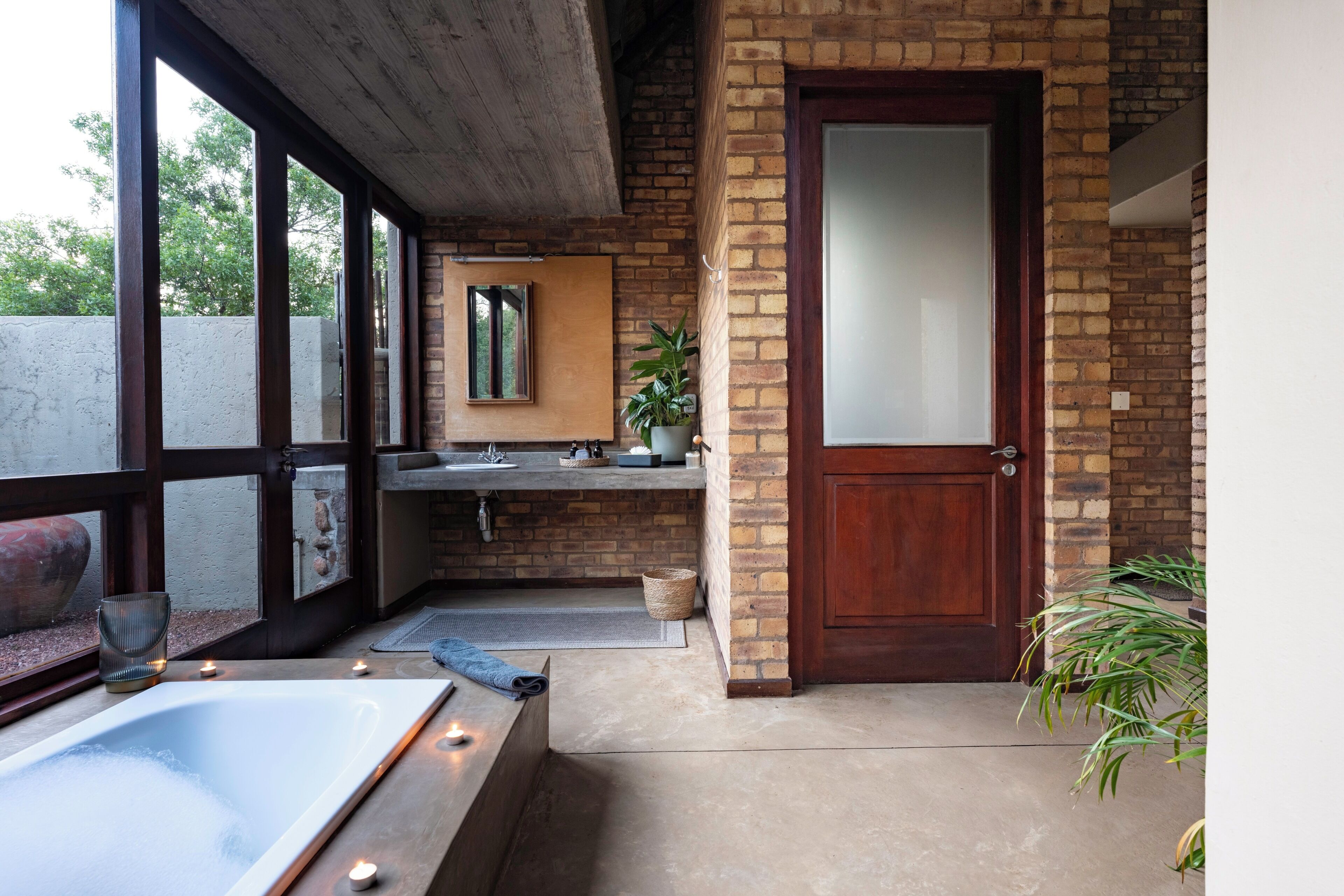 A bathroom with a bathtub, a sink, a mirror, and a door.