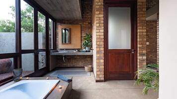 A bathroom with a bathtub, a sink, a mirror, and a door.