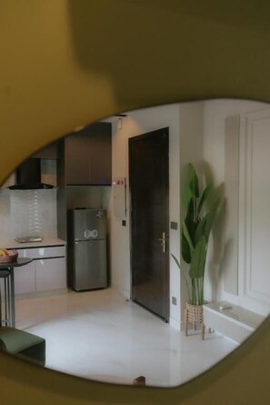 Een keuken met een koelkast, een eethoek met een tafel, en een potplant.