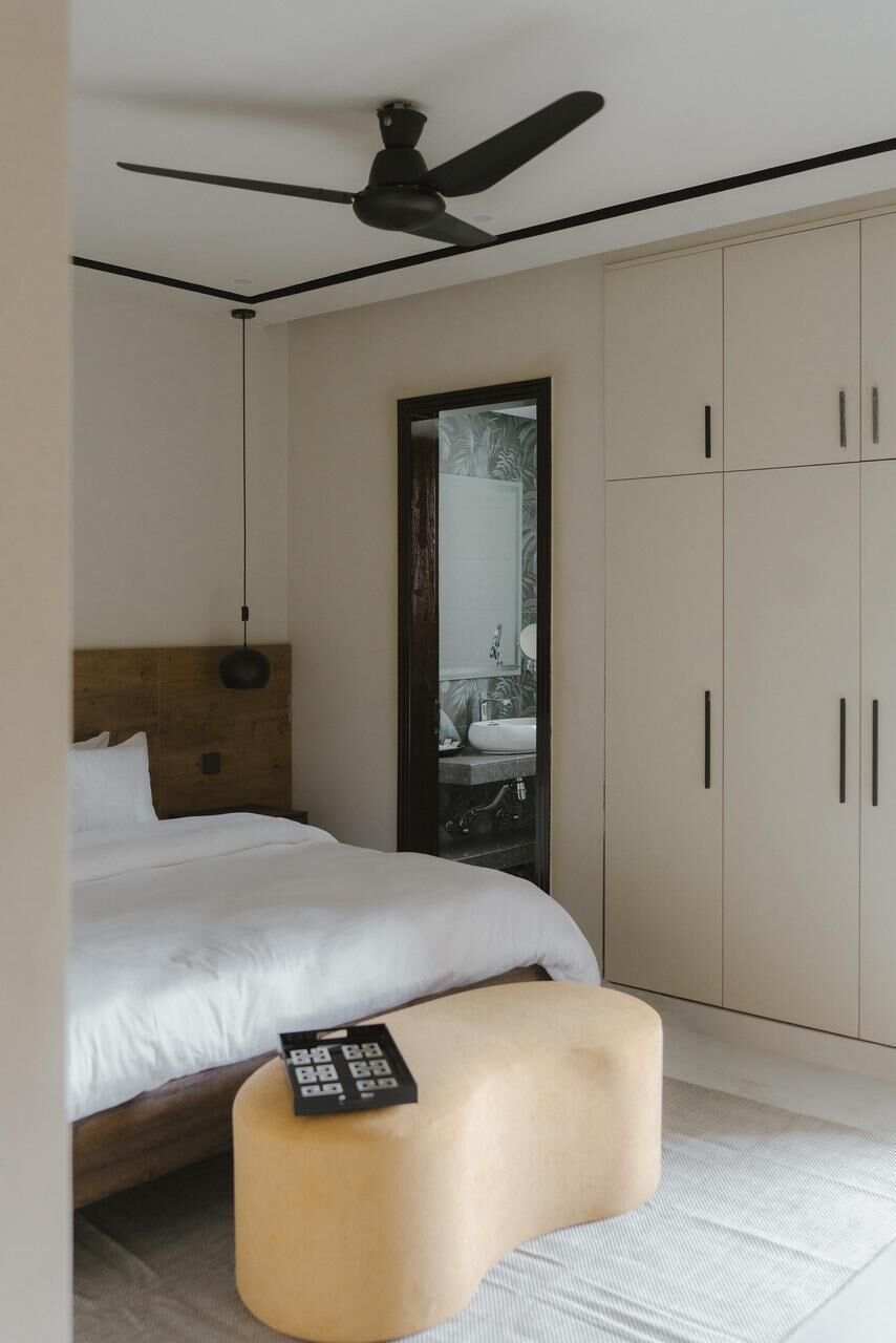 A bedroom with a bed, a bedside table, a ceiling fan, and a wardrobe.