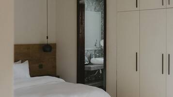 A bedroom with a bed, a bedside table, a ceiling fan, and a wardrobe.