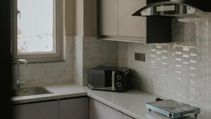 A kitchen with a microwave, a window, and a sink. - Address 12 Apartments Model Town Lahore (Lahore)