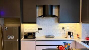 A modern kitchen with dark cabinetry, a microwave, a toaster, and a small dining table with a basket of snacks.