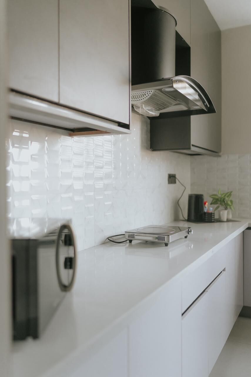 Een moderne keuken met witte kastjes, een zwarte afzuigkap en een geïntegreerd inductiekookveld.