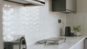 Una cocina moderna con armarios blancos, una campana extractora negra y una placa de inducción empotrada.