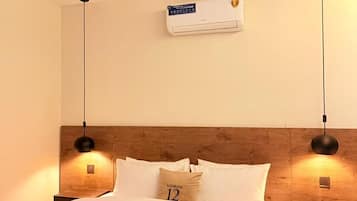 Une chambre d’hôtel équipée d’un lit, d’un ventilateur de plafond, d’un climatiseur mural et de deux lampes de chevet.