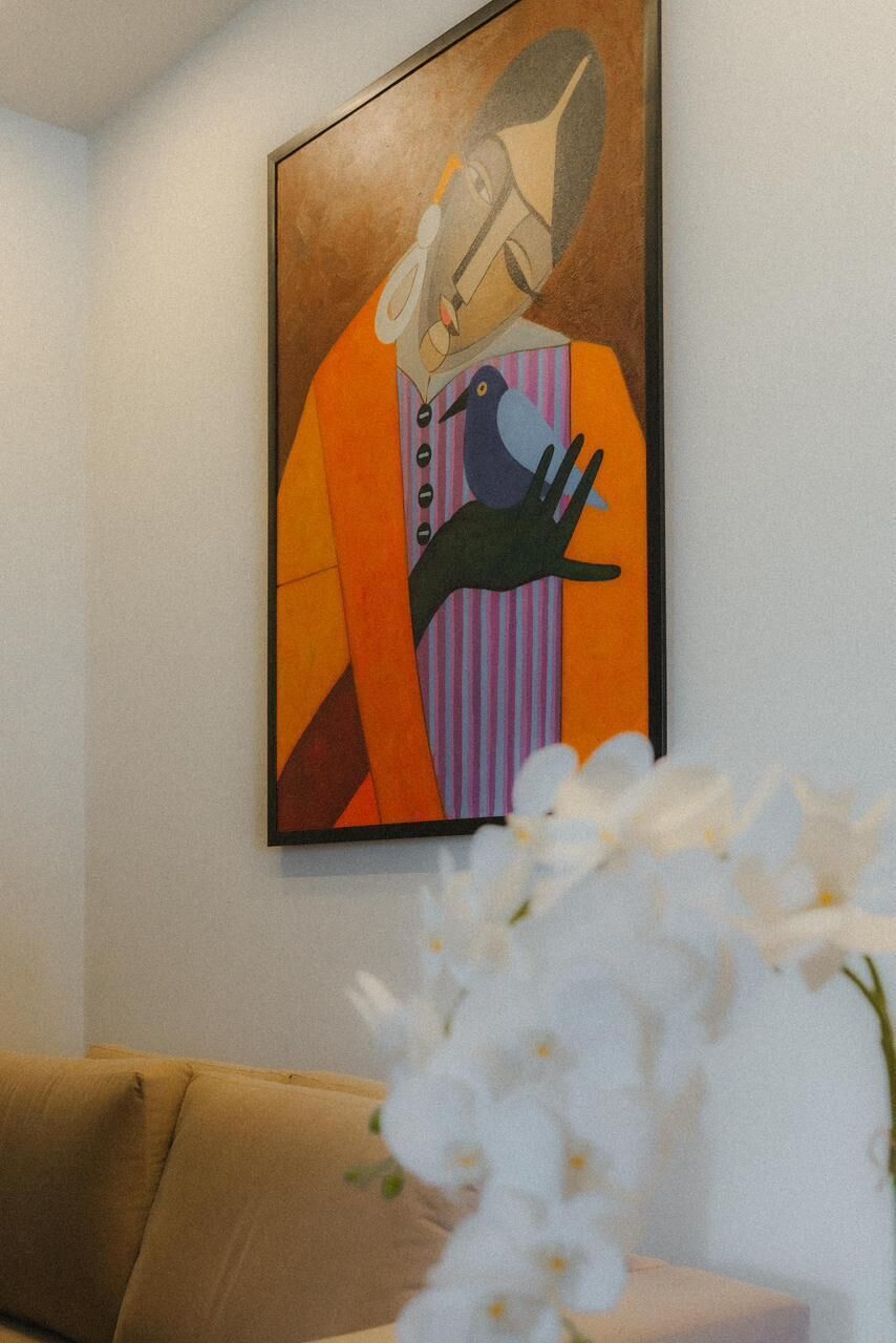 Un cuadro abstracto enmarcado con un pájaro y una mano en una pared.
