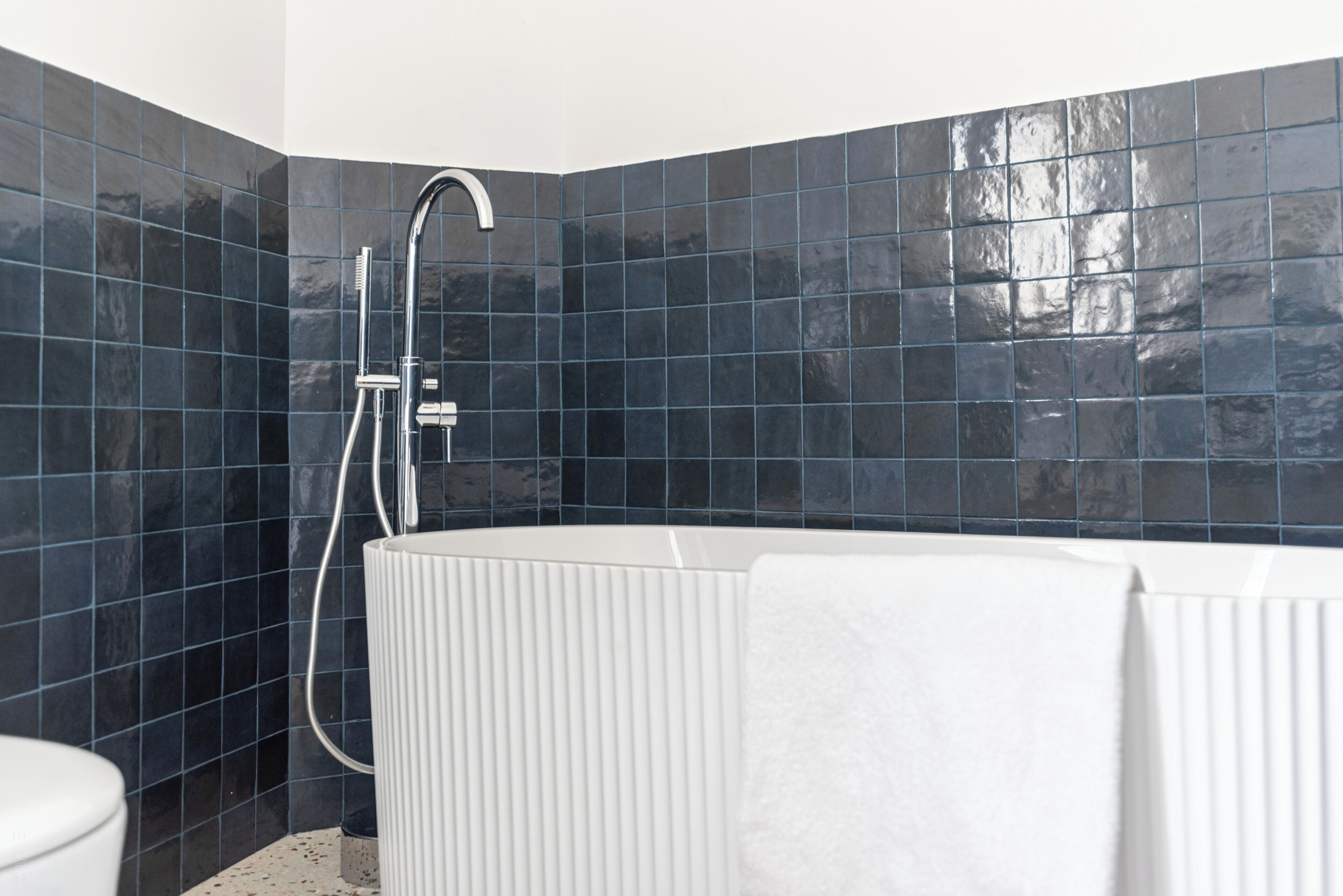 Een moderne badkamer met een douche in hoekopstelling, een wit bad en een toilet.