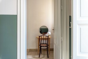 Ein Zimmer mit einem Holzbett, einem runden Spiegel und einem Tisch mit Lampe.