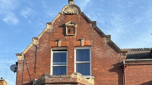 Un edificio in mattoni rossi con una finestra a bovindo, un abbaino e un piccolo balcone.