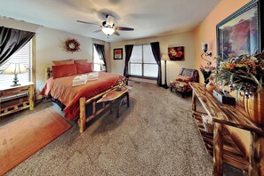 A bedroom with a bed, a desk, a chair, a ceiling fan, and a window with blinds. - Casa Aurora | Serene Sanctuary + Large Deck (Ruidoso)