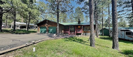 A cabin with a green roof, a covered porch, and a garage.