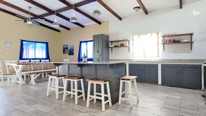 A kitchen with a bar area, white tiled walls, and a ceiling with exposed beams. - Rancho Al Mar Acajutla Beach Retreat (Acajutla)