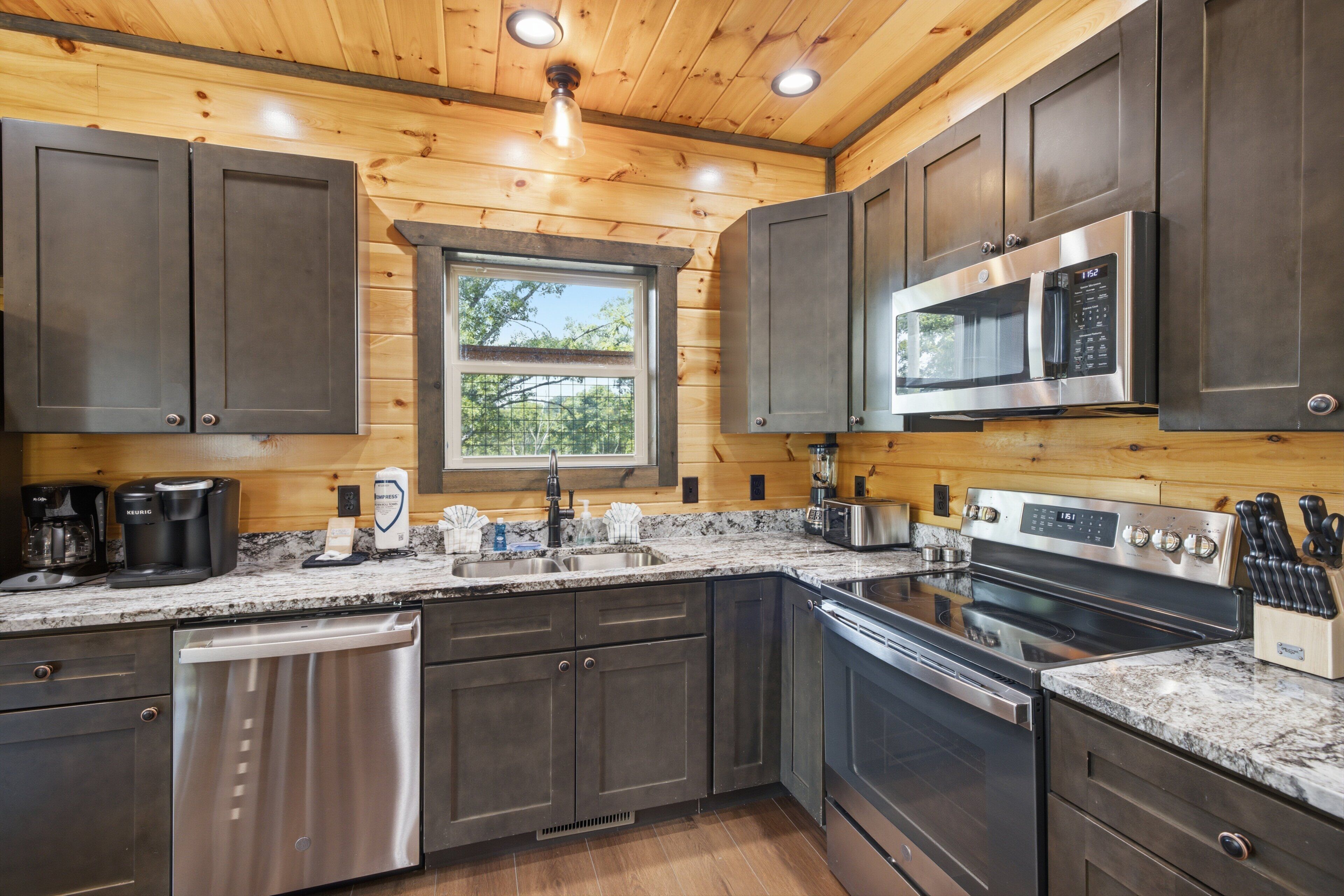A modern kitchen with stainless steel appliances, wooden cabinets, and a granite countertop.