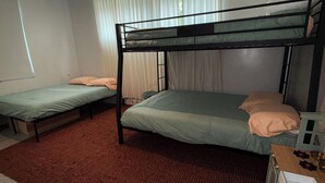 Ein Zimmer mit zwei Einzelbetten und einem Etagenbett, alles mit grüner Bettwäsche.