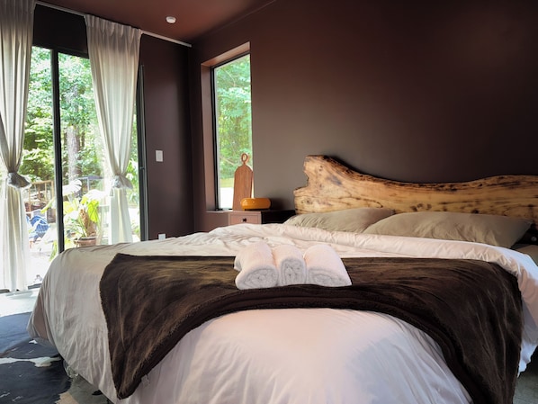 Un dormitorio con una cama grande, cabecera de madera y vistas a la vegetación.